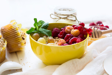 Healthy breakfast: muesli, honey, yogurt, muffins, coffee and fresh berries on white wooden background