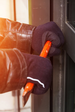 Burglar wearing leather coat breaking in a house