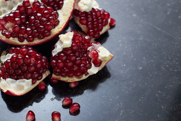 Red juicy pomegranate on dark marble background. Healthy, antioxidant, fresh, gourmet, delicious, organic fruit. Ingredient for grenadine. Close-up and copy space.
