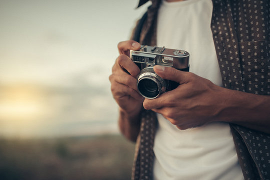 Beautiful portrait of close-up young man with vintage camera, photography nature, on nature, field, sunset, sky background. Travel. Picture for background.