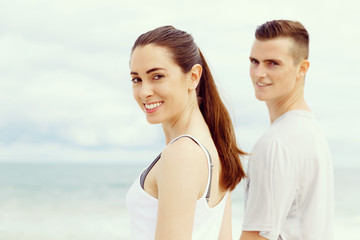 Fototapeta premium Young couple looking at camera while standing next to each other on beach