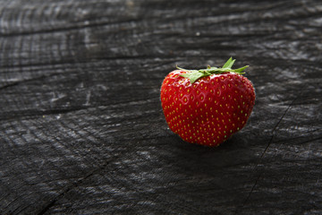 Red fresh strawberry on black rustic wood background