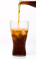 Bottle pouring coke in drink glass with ice cubes