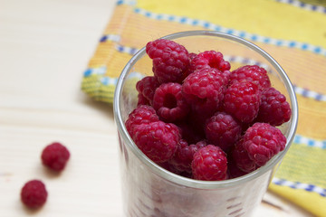 Simmer fresh raspberries in a glass on a wood and yellow background