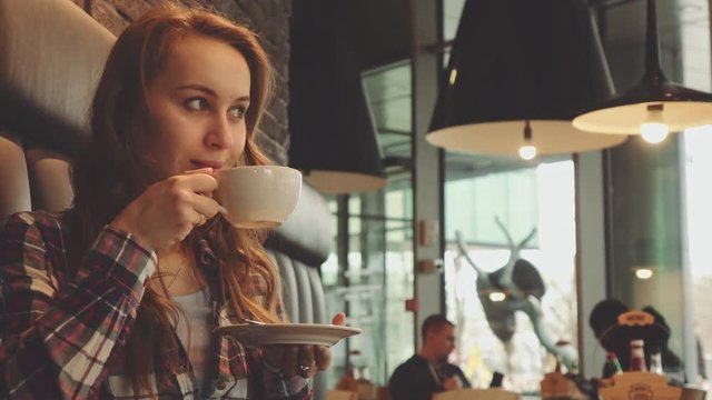 Woman drinking coffee in a cafe, 4K Slow Motion 120 fps. Stabilazed dolly shot. 