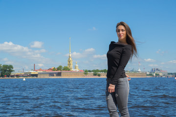 beautiful female tourist walks along the promenade on the background of the fortress