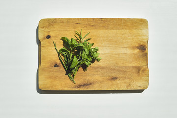 Fresh herbs lying on old wooden cutting board. Flat lay food ingredients background.