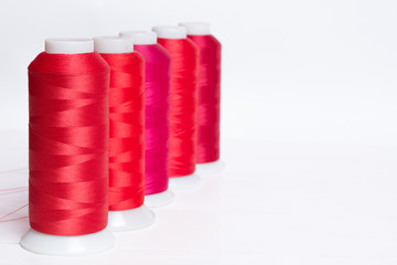 Red bobbin thread on white wooden table