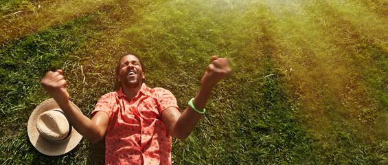 Happy young black man laying on the field