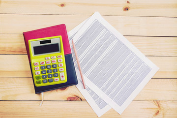 Financial accounting analysis on wooden background,yellow calculator ,pencil ,notebook