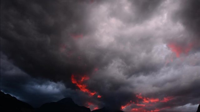 Storm, red clouds move across the sky. Tops of the mountains.