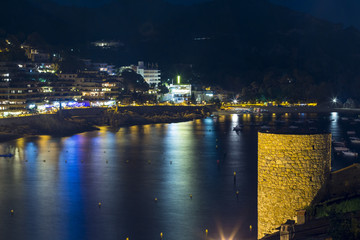 Fototapeta na wymiar Night view of ancient fortress and Badia de Tossa bay in Tossa d