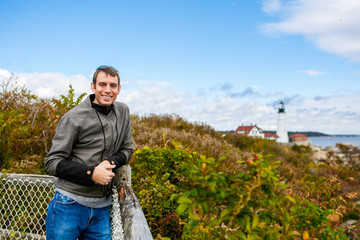 Smiling man tourist. At the background the Portland Headlight Lighthouse
