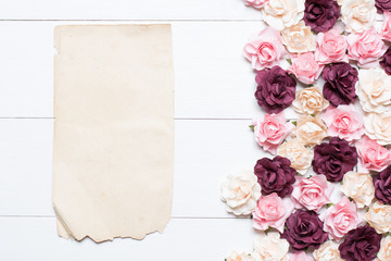 Old paper sheet with empty copyspace and roses on white wooden t