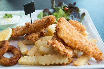 Fish and chips served with cream and vegetables