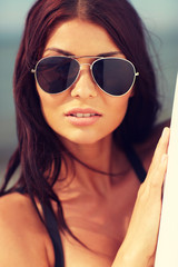Naklejka premium smiling young woman with surfboard on beach
