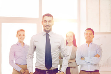 smiling businessman in office with team on back