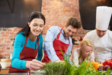 happy friends and male chef cooking in kitchen