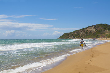 Walking man at wonderful undiscovered beach. Waves and footsteps at summer time in Corfu island, Greece