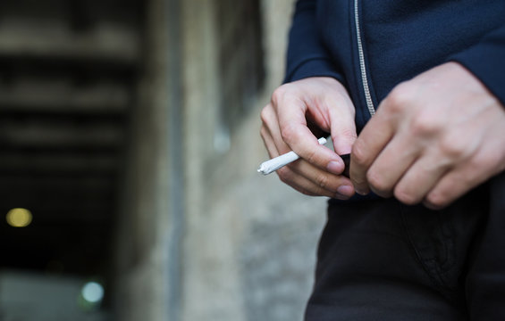 close up of addict hands with marijuana joint