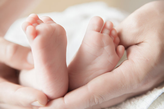 Parent holding his newborn baby's feet 