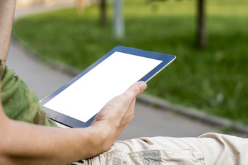 Young man using digital tablet at city park