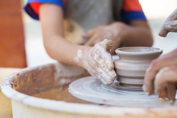 Hands of young potter, creating an earthen jar on the circle, cl