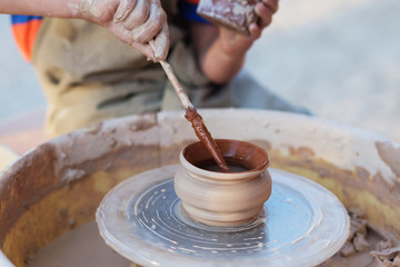 Hands of young potter, creating an earthen jar on the circle, cl