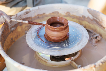 young potter, creating an earthen jar on the circle, close-up