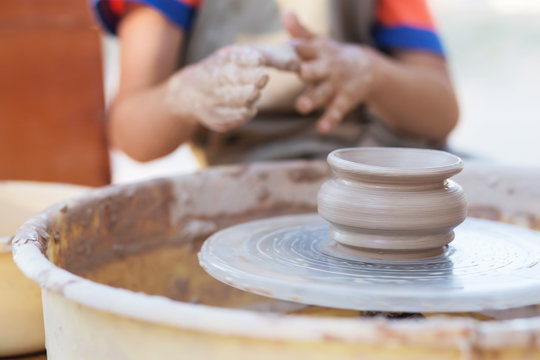 Hands of young potter, creating an earthen jar on the circle, cl