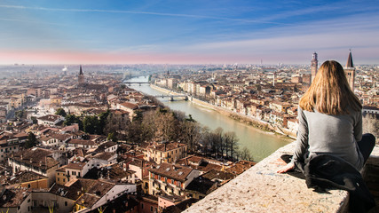 Girl looks the view of Verona at sunset from the terrace.