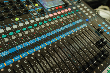 Black professional mixer with buttons and sliders to control the audio output power amplifier speakers.