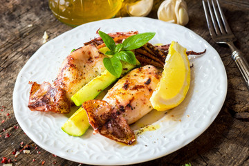Grilled squid with lemon and zucchini on wooden background