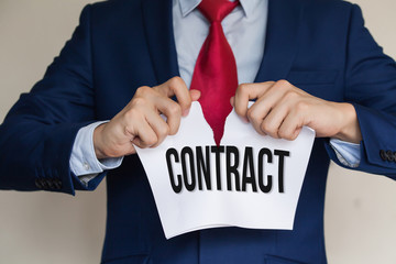 Businessman tearing CONTRACT apart on white background
