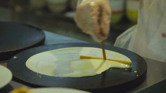 T-Shaped Stick For Rolling Out Dough on the Surface of the Pancake Makers. Chef With Special Stick Baking Pancakes. Cook Pancakes. Pancake Maker