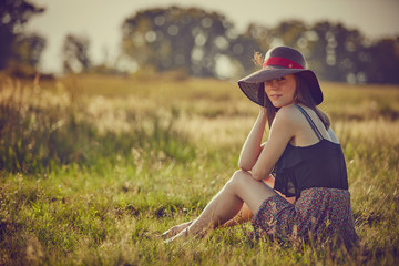 Giovane ragazza con cappello, serena al sole in campagna