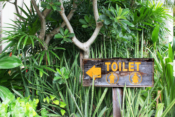 yellow text toilet sign in front of the garden