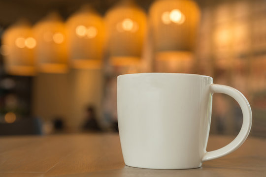 white coffee mug on the wooden table in the coffee shop with cozy