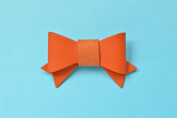 Orange artificial leather bow on blue background