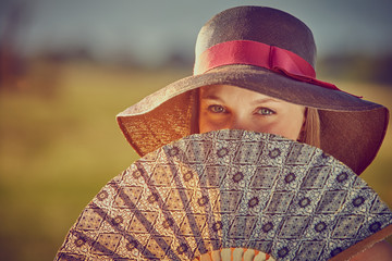 Ragazza in campagna con cappello e ventaglio