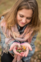 Girl walking in autumn park. Girl dressed in a coat and scarf. woman's hand, berries and acorns oak.