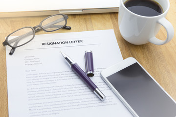 Businessman review his resignation letter on his desk before sending to his boss to quit his job with laptop computer and a cup of coffee.