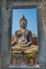 View of Sitting Buddha statue through stone door in the Ancient temple Thailand