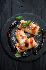 Crepes with cottage cheese, jam and sugar powder, above view