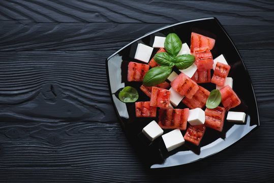 Salad With Grilled Watermelon And Feta On A Black Wooden Surface