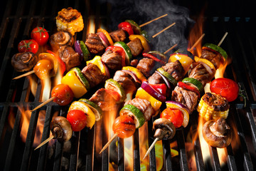 Meat kebabs with vegetables on flaming grill - obrazy, fototapety, plakaty