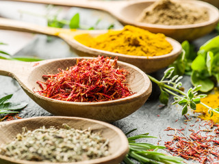 Assortment of colorful spices in the wooden spoons.