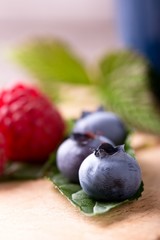 Detail of several blue blueberries on green leaf
