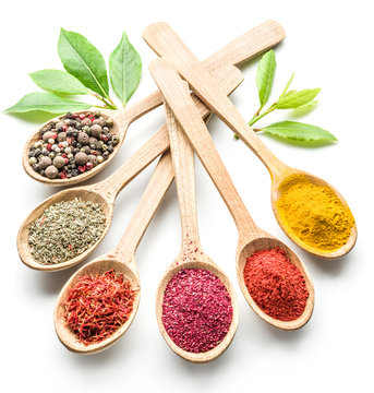 Assortment of colorful spices in the wooden spoons on the white