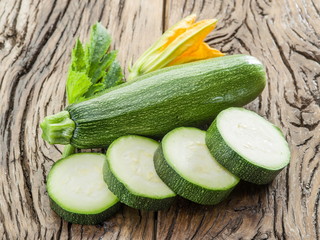 Zucchini with slices and zucchini flowers on a wooden table.